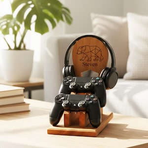 K&ouml;nnte beinhalten: Gaming-Station aus Holz mit geometrischem B&auml;r-Design und dem Namen "Steven". Die Station h&auml;lt zwei schwarze Gamecontroller und ein Paar schwarze Kopfh&ouml;rer. Das Design befindet sich auf einem Holzst&auml;nder, ideal zum Organisieren von Gaming-Zubeh&ouml;r.