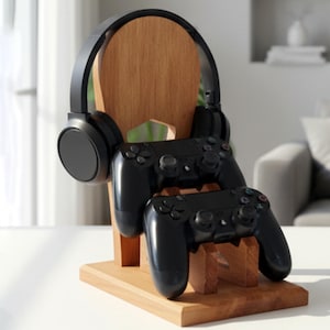 K&ouml;nnte beinhalten: Ein Holzst&auml;nder f&uuml;r Kopfh&ouml;rer und Gamecontroller. Der St&auml;nder aus hellbraunem Holz h&auml;lt ein Paar schwarze Kopfh&ouml;rer und zwei schwarze Gamecontroller. Das Design ist schlicht und modern.