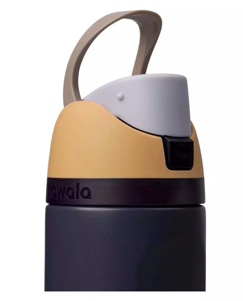 Puede incluir: Primer plano de una botella de agua con asa beige y tapa gris claro. El cuerpo de la botella es azul marino, y la secci&oacute;n superior es beige y gris. La palabra "awala" est&aacute; impresa en la botella.