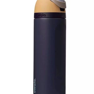 Puede incluir: Una botella de agua aislada azul marino con tapa beige y gris. La botella tiene la palabra "owala" impresa en el lateral. Dise&ntilde;ada para mantener las bebidas fr&iacute;as o calientes.