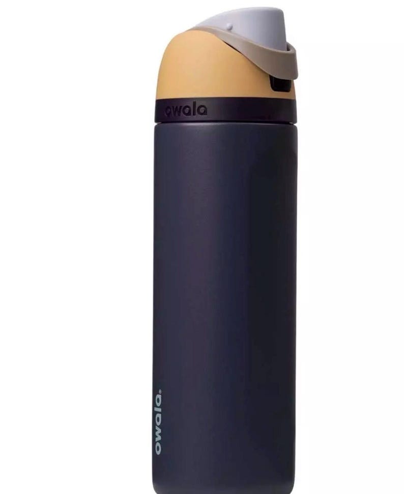 Puede incluir: Una botella de agua aislada de color azul marino con una tapa beige y gris. La botella tiene la palabra "owala" impresa en el lateral. La tapa tiene un dise&ntilde;o abatible para facilitar el acceso. Esta botella reutilizable est&aacute; dise&ntilde;ada para la hidrataci&oacute;n.