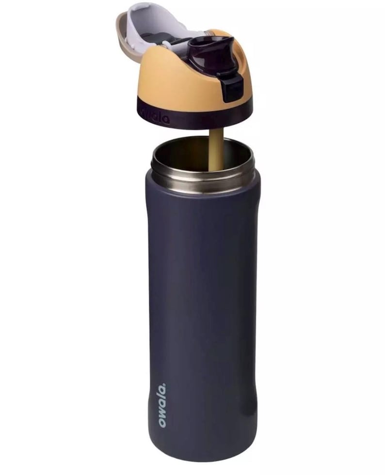 Puede incluir: Una botella de agua aislada de color azul marino con tapa abatible. La tapa es de color beige y morado, con una boquilla blanca. La botella tiene un borde de acero inoxidable y una pajita. La marca "owala" est&aacute; impresa en el lateral.