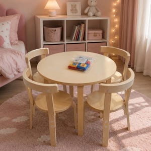 May include: A round, light-colored wooden table with four matching chairs arranged around it. A clear plastic bag containing colorful building blocks sits in the center of the table. The furniture set is made of smooth, natural wood with a light finish.