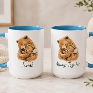 Light blue handle angel baby mug set with teddy bear memorial artwork, personalized with Isaiah and Always Together, photographed in a cozy neutral home setting.