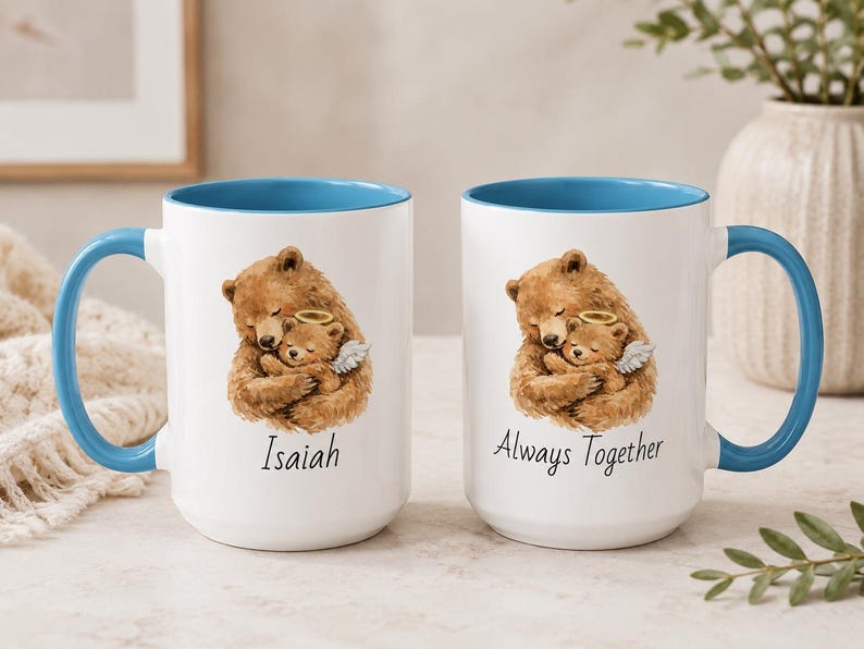 Light blue handle angel baby mug set with teddy bear memorial artwork, personalized with Isaiah and Always Together, photographed in a cozy neutral home setting.