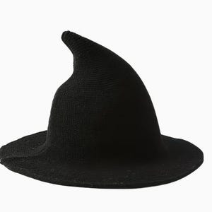 May include: A solid black knitted hat featuring a tall, pointed crown that curves slightly to one side and a wide, circular brim. The texture of the hat is consistent throughout, showing a fine knit pattern in a deep, dark black color.