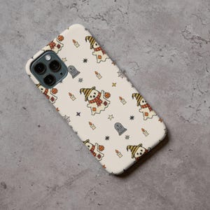 Smartphone protective case mockup printed with retro needlework halloween ghost pattern on a gray concrete surface.