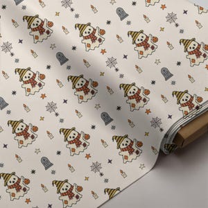 Seamless cross-stitch fabric roll mockup featuring cute ghost, candles, and gravestone folk art pattern for autumn sewing projects.