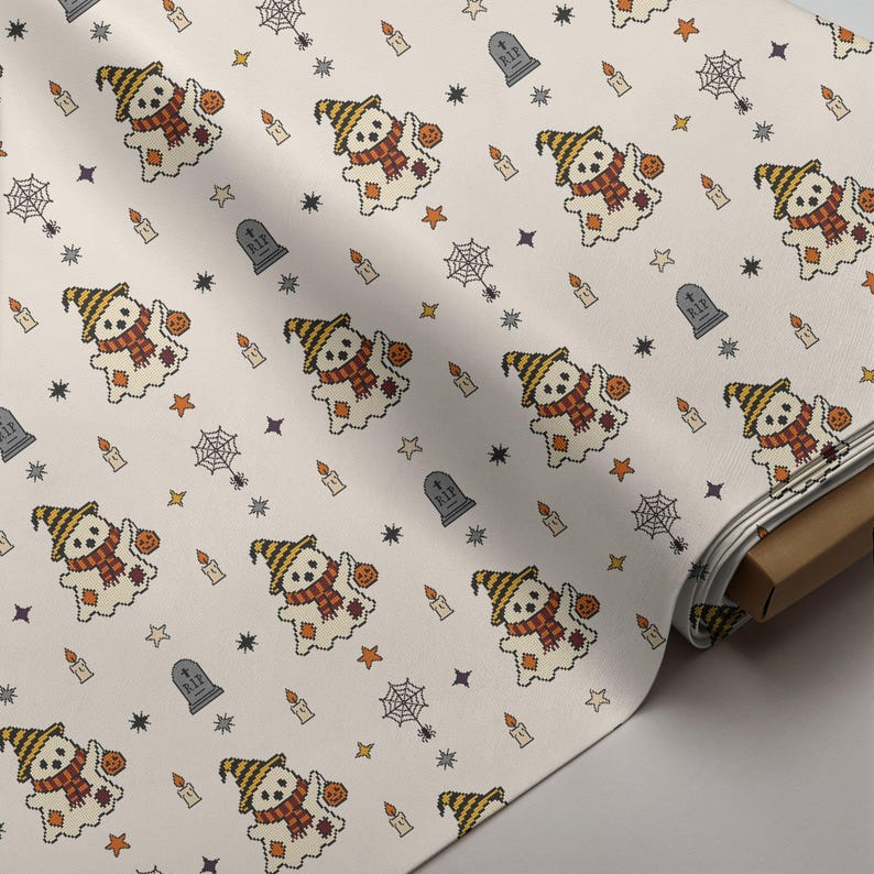 Seamless cross-stitch fabric roll mockup featuring cute ghost, candles, and gravestone folk art pattern for autumn sewing projects.