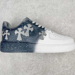 Puede incluir: Zapatilla blanca y azul marino con detalles de cruces grises. El zapato presenta un diseño degradado, que transiciona de azul marino con motas blancas a blanco. Las cruces grises están colocadas en la sección azul marino.