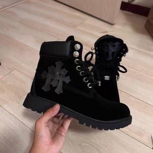 Può includere: Stivaletti neri in camoscio con suola spessa. Gli stivali presentano un design a croce sul lato e occhielli color argento. Hanno un colletto imbottito e una chiusura con lacci.