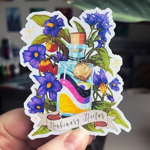 Puede incluir: Una pegatina que presenta una botella de vidrio transparente con un tapón de corcho, llena de un líquido colorido que representa la bandera no binaria. La botella está rodeada de flores moradas, bayas rojas y hojas verdes. La pancarta dice "Nonbinary Nectar".
