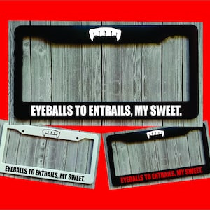 May include: Three license plate frames with the text "EYEBALLS TO ENTRAILS, MY SWEET." The frames are black, white, and black with red text. Each frame has a white vampire teeth graphic.