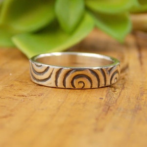 Peut inclure: Une bague en argent avec un motif en spirale gravé sur la surface.