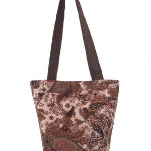 Pode incluir: Uma sacola com um padr&atilde;o paisley em tons de marrom e bege. A sacola tem al&ccedil;as marrons e formato retangular. O design paisley apresenta formas florais e de l&aacute;grima. A sacola &eacute; feita de tecido.