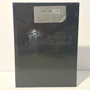May include: A black Final Fantasy XV Collector's Edition hardcover strategy guide. The cover features the game title in silver text and a sticker detailing contents including a 24 by 36 inch map poster, a 32 page art gallery, and lithograph.