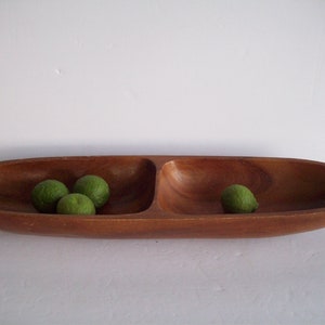 May include: A wooden serving bowl with two compartments, filled with green limes.