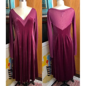 May include: A long-sleeved, burgundy velvet dress with a sheer mesh panel on the back. The dress has a V-neckline and a fitted bodice.