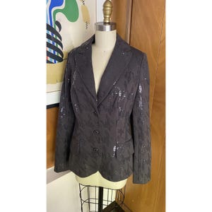 K&ouml;nnte beinhalten: Ein schwarzer Blazer mit Pailletten, Knopfleiste und langen &Auml;rmeln.