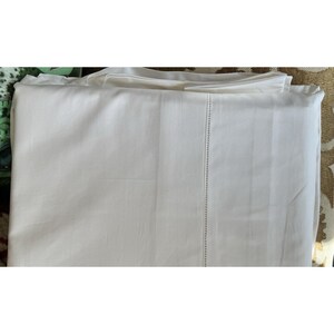 Pu&ograve; includere: Lenzuolo bianco piegato con un bordo verticale cucito. Il lenzuolo &egrave; realizzato in un tessuto liscio, forse cotone. Il lenzuolo &egrave; ben piegato, suggerendo che sia nuovo o appena lavato. Lo sfondo &egrave; un tessuto fantasia.