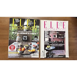 Puede incluir: Dos ejemplares de la revista Elle Decoration, una revista francesa de decoraci&oacute;n de interiores. La portada de la revista de la izquierda presenta una cocina con una encimera blanca y un fregadero con un grifo cromado. La portada de la revista de la derecha presenta una cocina con una pared rosa y una encimera blanca. Ambas portadas presentan el texto "Elle Decoration" en blanco.