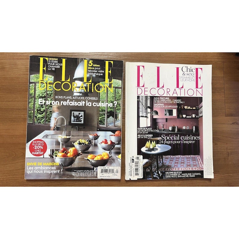 Puede incluir: Dos ejemplares de la revista Elle Decoration, una revista francesa de decoraci&oacute;n de interiores. La portada de la revista de la izquierda presenta una cocina con una encimera blanca y un fregadero con un grifo cromado. La portada de la revista de la derecha presenta una cocina con una pared rosa y una encimera blanca. Ambas portadas presentan el texto "Elle Decoration" en blanco.