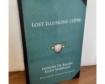 May include: A hardcover book titled "Lost Illusions (1898)" by Honoré de Balzac and Ellen Marriage. The book has a teal cover with black trim and the text in white. The cover also features a crest and the words "Kessinger Legacy Reprints."