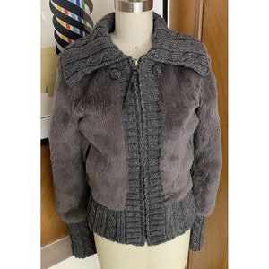 May include: A grey faux fur jacket with a knitted collar and cuffs. The jacket has a zip fastening and two buttons on the front.