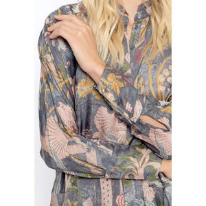 Op de afbeelding: Een lang mouw shirt met een grijze achtergrond en een kleurrijk bloemenpatroon. Het shirt heeft een knoopsluiting aan de voorkant en een kraag.