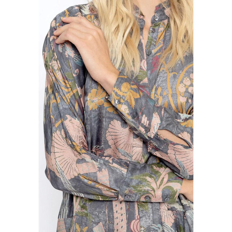 Op de afbeelding: Een lang mouw shirt met een grijze achtergrond en een kleurrijk bloemenpatroon. Het shirt heeft een knoopsluiting aan de voorkant en een kraag.