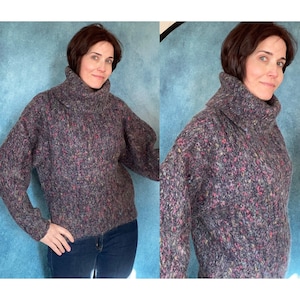 Può includere: Un maglione grigio a collo alto morbido e soffice con un motivo a macchie multicolori. Il maglione ha una vestibilità rilassata e maniche lunghe.