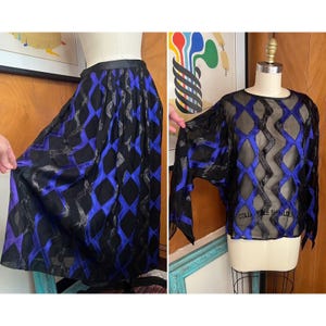 May include: A black and blue patterned skirt and a sheer black and blue top with a geometric design. Both garments are made of a silky fabric.