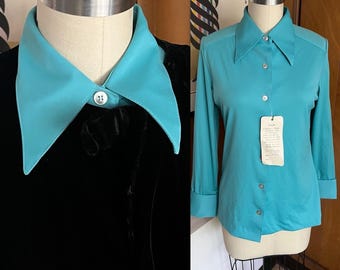 May include: Two vintage shirts are displayed. One is a black velvet jacket with a turquoise collar. The other is a turquoise button-down shirt with long sleeves and a collar. A tag hangs from the shirt.