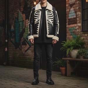 May include: Black leather jacket with a cream shearling collar and trim. The jacket has a white skeleton rib cage design on the front and sleeves. The model is wearing black jeans and boots.