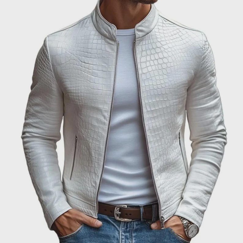 Pode incluir: Casaco de couro branco texturizado com fecho de correr e gola alta. O casaco apresenta um padr&atilde;o de pele de crocodilo e dois bolsos laterais. Usado com uma camiseta branca, jeans azul e cinto castanho.