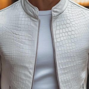 Pode incluir: Casaco de couro branco texturizado com padr&atilde;o de pele de crocodilo. O casaco tem gola alta e z&iacute;per completo. Usado sobre uma camiseta branca.
