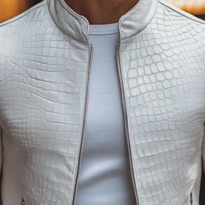 Pode incluir: Casaco de couro branco texturizado com padr&atilde;o de pele de crocodilo. O casaco tem gola alta e z&iacute;per completo. Usado sobre uma camiseta branca.
