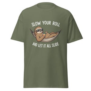 Può includere: T-shirt verde oliva con un bradipo dei cartoni animati con occhiali da sole, che si rilassa in un'amaca mentre tiene in mano una bevanda. Il testo "SLOW YOUR ROLL AND LET IT ALL SLIDE" è stampato.