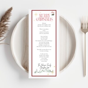 May include: A festive Christmas menu card with a burgundy border, displaying the words "MERRY CHRISTMAS" in red script. The card features a poem and the family name "The Johnson Family Christmas 2025". It rests on a white plate with a fork.