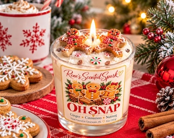 May include: A clear glass candle with a label reading Rene's Scented Spark OH SNAP Ginger Cinnamon Nutmeg Hand Poured in Clearwater, FL 9 oz (255 g). The candle features two gingerbread man wax embeds and a lit wick.