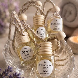 May include: A collection of small glass bottles with wooden tops, each labeled with a different name and scent blend. The bottles are filled with a light yellow liquid and are suspended by a rope. The labels include "Tristan blend", "Chloe blend", "(Any Name) blend", and "Personalize here blend".