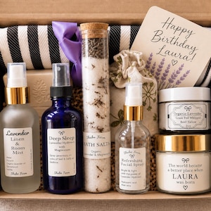 May include: A gift box containing a black and white striped cloth, a glass tube of bath salts, a small patterned pouch, and a card reading Happy Birthday Laura. Includes bottles of lavender linen mist, deep sleep spray, facial spray, and two jars.