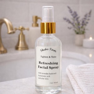 May include: A clear glass bottle of Shabo Farm Refreshing Facial Spray with a gold-colored cap. The label reads "Tighten & Tone" and lists ingredients like lavender hydrosol, hyaluronic acid, and aloe vera. The bottle contains 2 fl oz.