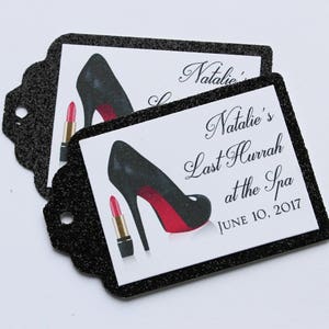 Puede incluir: Etiquetas de favor negras y blancas con detalles de purpurina. Las etiquetas presentan un zapato de tacón alto negro con suela roja y un lápiz labial rojo. El texto en la etiqueta dice "Natalie's Last Hurrah at the Spa June 10, 2017".