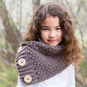Puede incluir: Un cuello de punto de ganchillo marrón con botones de madera. El cuello lo lleva puesto una persona joven con el pelo largo y castaño.