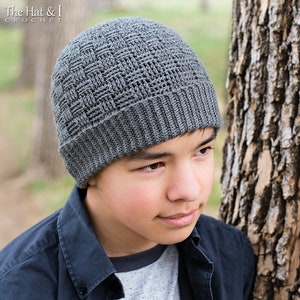 May include: A gray crocheted beanie with a textured pattern. The beanie is worn by a person with dark hair and brown eyes.