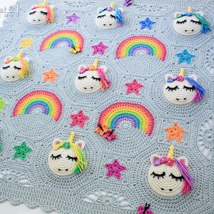 Puede incluir: Una manta de beb&eacute; de crochet con un fondo azul claro que presenta un patr&oacute;n repetitivo de arco&iacute;ris, estrellas y aplicaciones de unicornio. The Hat & I Crochet est&aacute; impreso en la esquina superior izquierda.