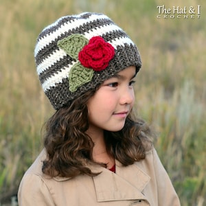 May include: A brown and white striped crochet hat with a red crocheted flower and green leaves.