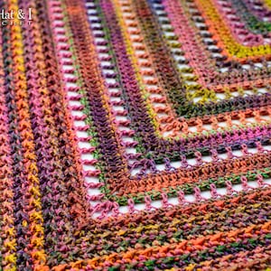 Puede incluir: Primer plano de un chal de ganchillo multicolor con un patr&oacute;n de punto texturizado. El chal est&aacute; hecho con un hilo degradado que pasa del naranja al morado al verde.