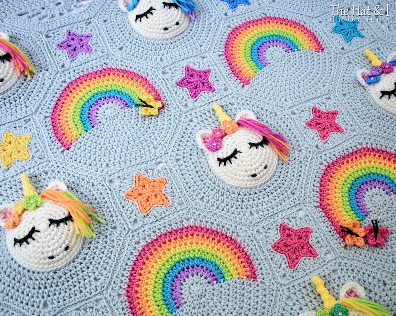 Puede incluir: Una manta de beb&eacute; de crochet con un fondo azul claro que presenta arco&iacute;ris, estrellas y unicornios. La manta est&aacute; hecha con hilo de colores y tiene una textura suave.